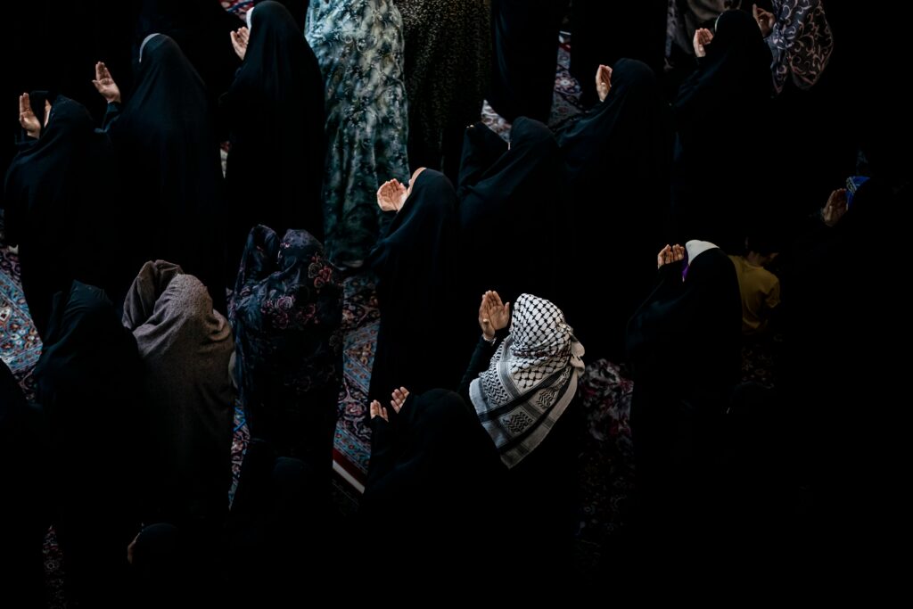 Muslim women in black attire praying during a religious gathering in Karbala, Iraq.